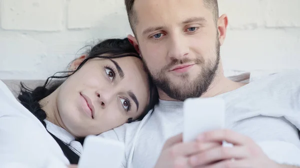 Cheerful man and woman using smartphones at home — Stock Photo