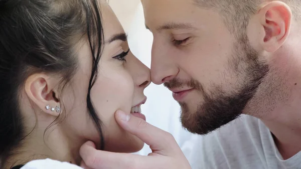 Primer plano de hombre barbudo tocando cara de mujer morena feliz - foto de stock