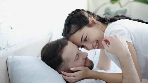 Felice giovane donna volto toccante di uomo barbuto in camera da letto — Foto stock