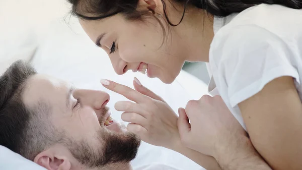 Cheerful woman touching face of happy bearded boyfriend — Photo de stock