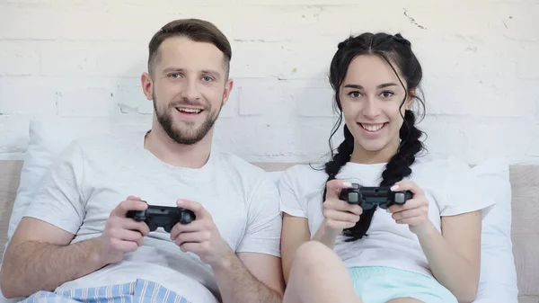 KYIV, UKRAINE - JUNE 17, 2021: young pleased couple playing video game in bedroom — Photo de stock