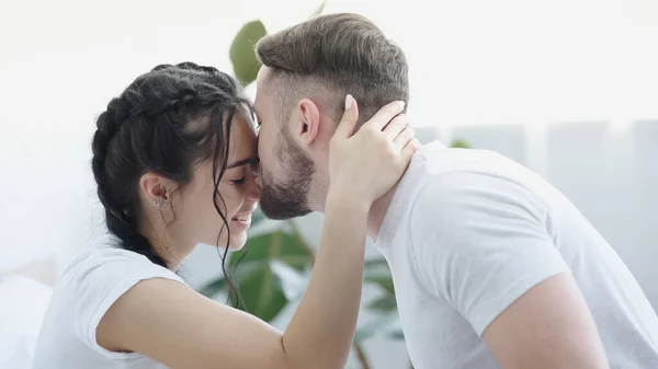 Barbudo hombre besar frente de sonriente novia - foto de stock