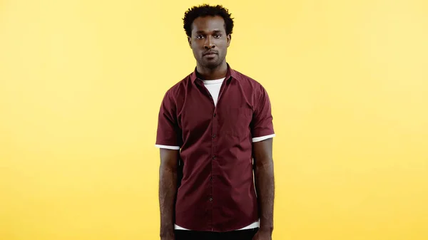 Lockiger afrikanisch-amerikanischer Mann im Hemd, der isoliert auf gelb in die Kamera blickt — Stockfoto