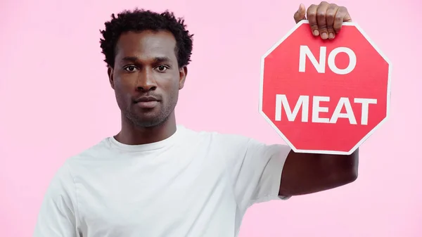 Encaracolado afro-americano homem em branco t-shirt segurando sinal sem letras de carne isolado em rosa — Fotografia de Stock