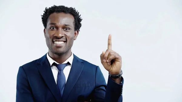 Cheerful african american businessman showing idea gesture isolated on blue — Stock Photo