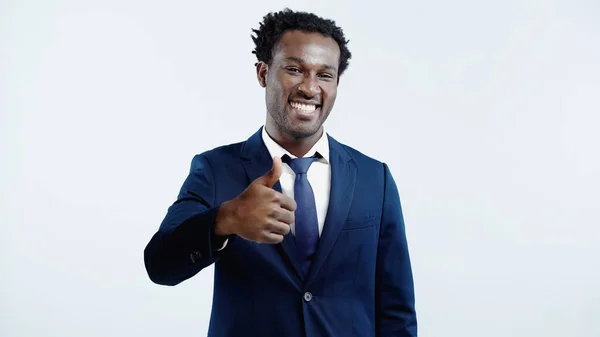 Positive african american businessman in formal wear showing thumb up isolated on blue — Stock Photo