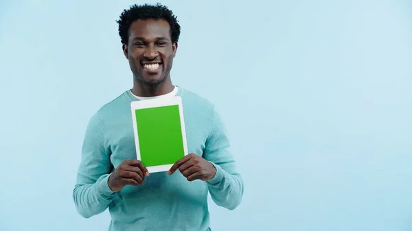 Felice uomo africano americano in possesso di tablet digitale con schermo verde isolato su blu — Foto stock