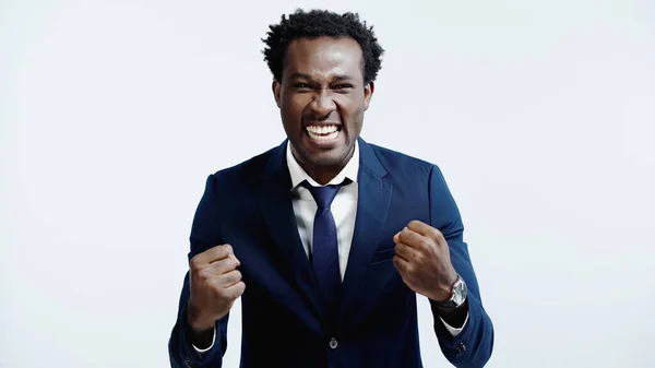 Emocionado hombre de negocios afroamericano con los puños cerrados aislados en azul - foto de stock