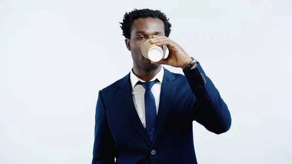 Curly african american businessman drinking coffee to go isolated on blue — Stock Photo