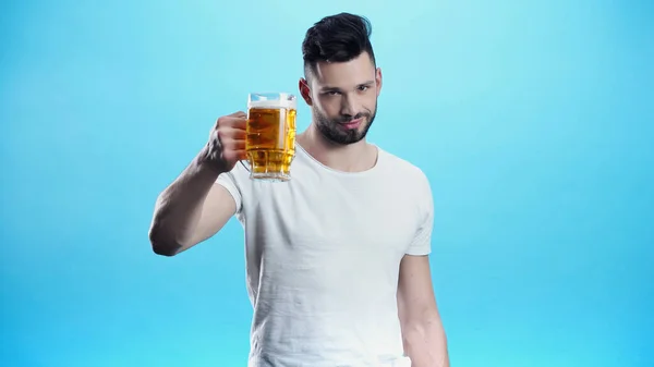 Pleased man holding mug of cold beer isolated on blue — Stock Photo