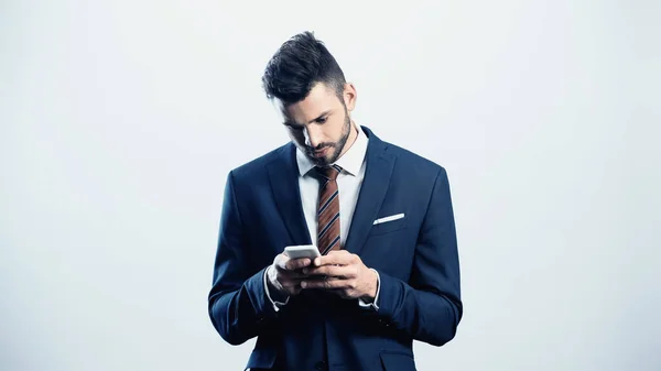 Young serious businessman chatting on mobile phone isolated on white — Stock Photo