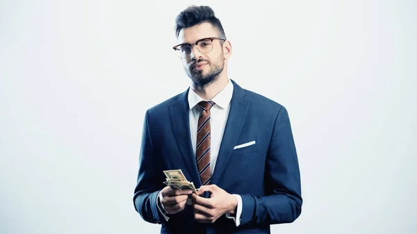 Confident businessman looking at camera while holding dollars isolated on white — Stock Photo