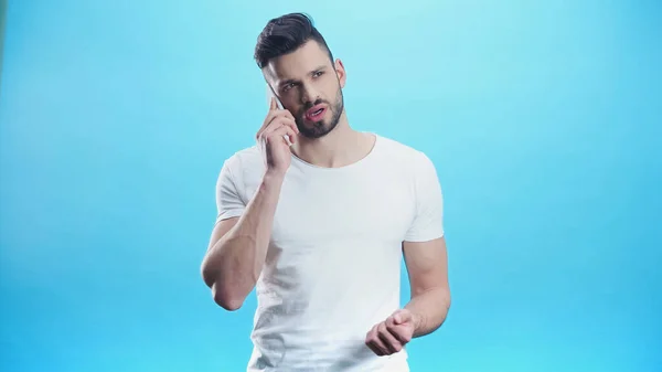 Offended man calling on mobile phone isolated on blue — Stock Photo