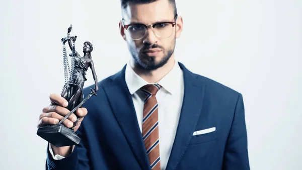 Blurred businessman holding justice statuette while looking at camera isolated on white — Stock Photo