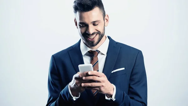 Alegre hombre de negocios mensajes de texto en el teléfono celular aislado en blanco - foto de stock