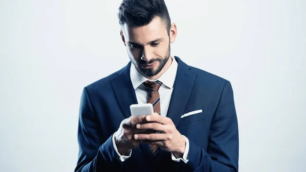 Sonriente mensajería de hombre de negocios en el teléfono móvil aislado en blanco - foto de stock