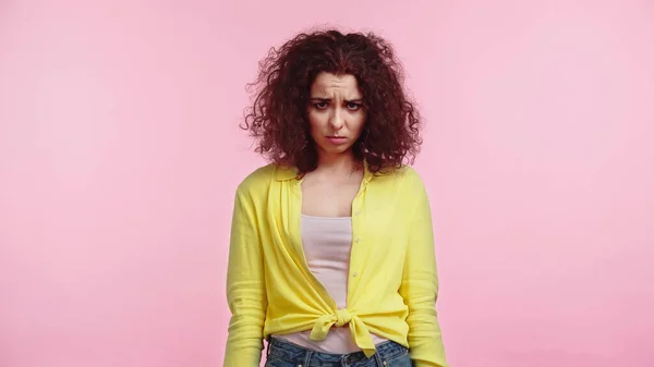 Offended and curly woman standing isolated on pink — Stock Photo