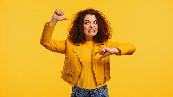 Dissatisfied young woman showing thumbs down isolated on yellow — Stock Photo