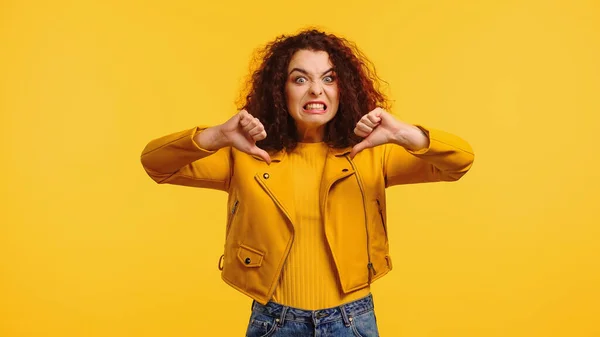 Mujer joven disgustado mostrando pulgares hacia abajo aislado en amarillo - foto de stock