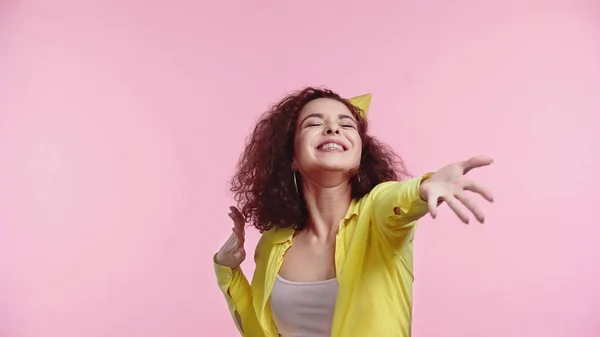Zufriedene junge Frau in Partymütze mit ausgestreckter Hand auf rosa — Stockfoto