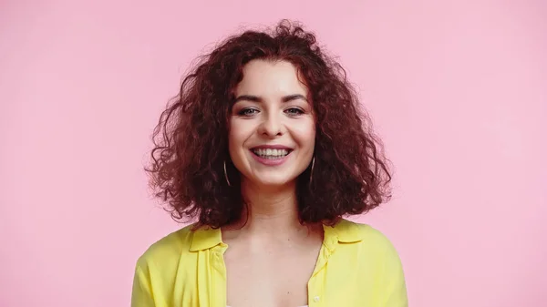 Sorridente jovem e encaracolado mulher olhando para câmera isolada em rosa — Fotografia de Stock