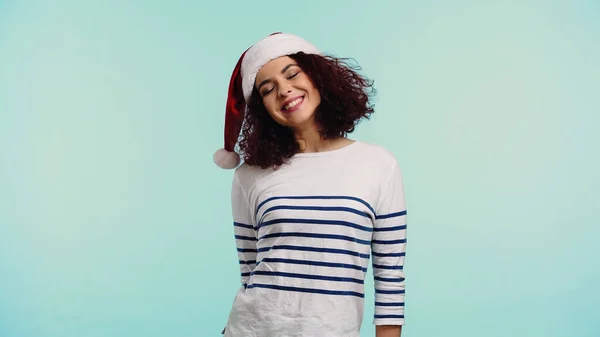 Freudige junge Frau mit Weihnachtsmütze auf blauem Grund — Stockfoto