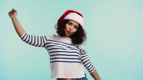 Young woman in santa hat pouting lips isolated on blue — Stock Photo