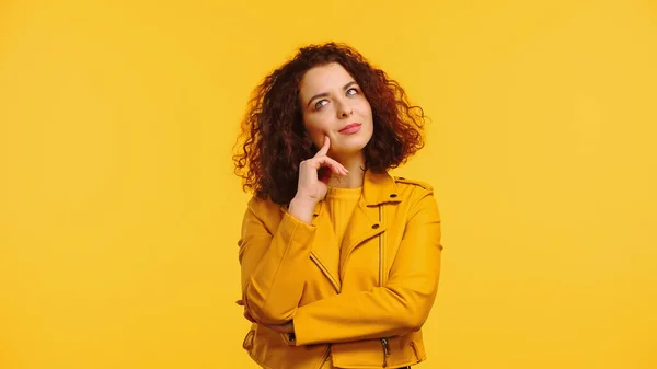 Mujer joven pensativa en chaqueta aislada en amarillo - foto de stock