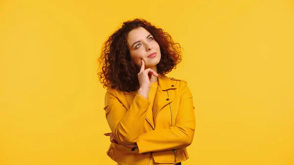 Nachdenkliche junge, lockige Frau in Jacke, isoliert auf gelb — Stockfoto