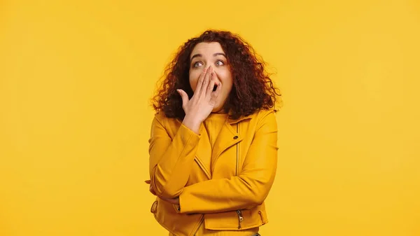 Amazed young woman covering mouth isolated on yellow — Stock Photo