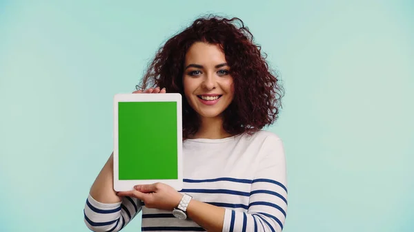 Feliz joven mujer sosteniendo tableta digital con pantalla verde aislado en azul - foto de stock