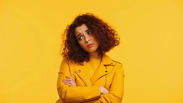 Upset young woman in leather jacket standing with crossed arms isolated on yellow — Stock Photo