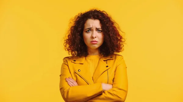 Sad young woman in leather jacket standing with crossed arms isolated on yellow — Stock Photo