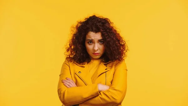 Offended young woman in leather jacket standing with crossed arms isolated on yellow — Stock Photo