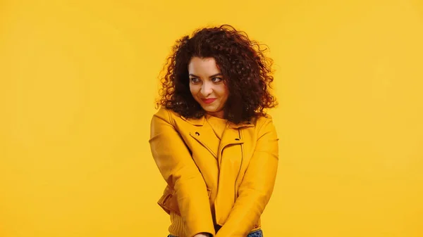 Shy young woman in leather jacket isolated on yellow — Stock Photo