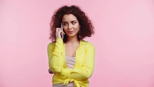 Curly woman standing while talking on cellphone isolated on pink — Stock Photo