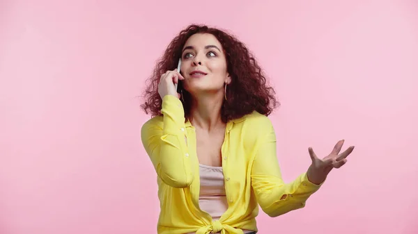 Junge Frau gestikuliert beim Telefonieren auf Smartphone isoliert auf rosa — Stockfoto