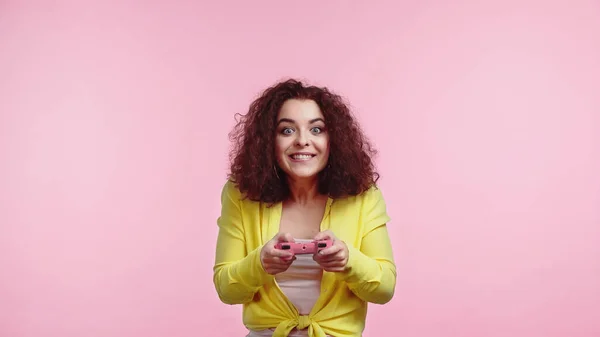 KYIV, UCRANIA - 30 de junio de 2021: Joven alegre sosteniendo el joystick y jugando aislada en rosa - foto de stock