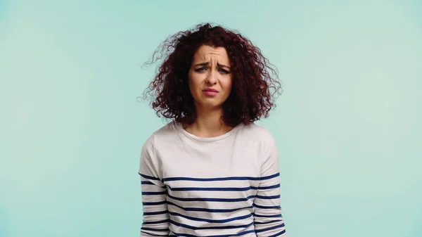 Upset young woman in striped long sleeve shirt isolated on blue — Stock Photo