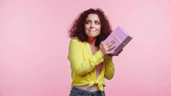 Curiosa donna in possesso di scatola regalo avvolto isolato su rosa — Foto stock