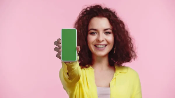 Розмита і щаслива жінка тримає смартфон із зеленим екраном ізольовано на рожевому — стокове фото