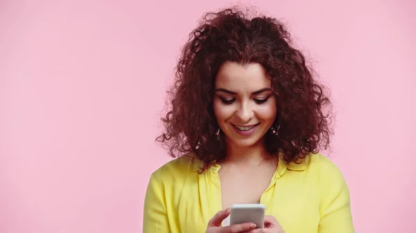 Happy young woman chatting on smartphone isolated on pink — Stock Photo