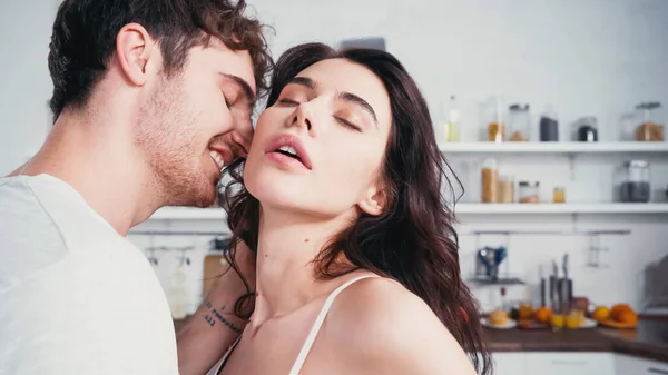 Mulher sexy com olhos fechados perto de sorrir homem na cozinha — Fotografia de Stock