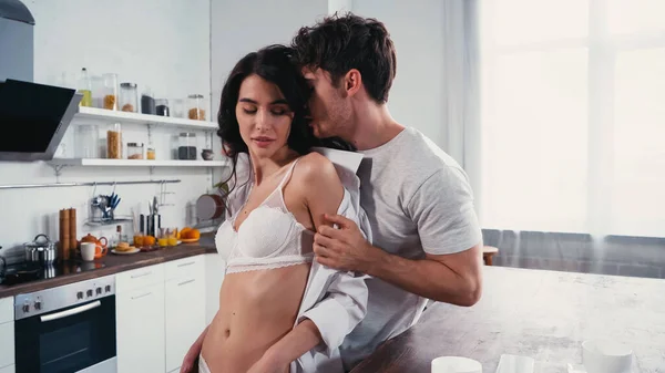 Young man taking off shirt from hot woman in white bra — Stock Photo