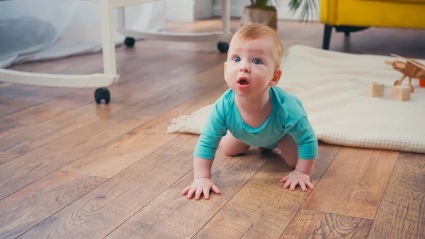 Surprised infant boy crawling on floor in living room — Stock Photo