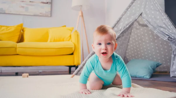 Happy infant boy crawling on blanket near tipi in living room — Stock Photo