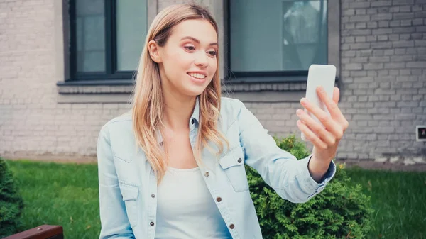 Щасливий студент має відеодзвінок на смартфон біля будівлі — стокове фото