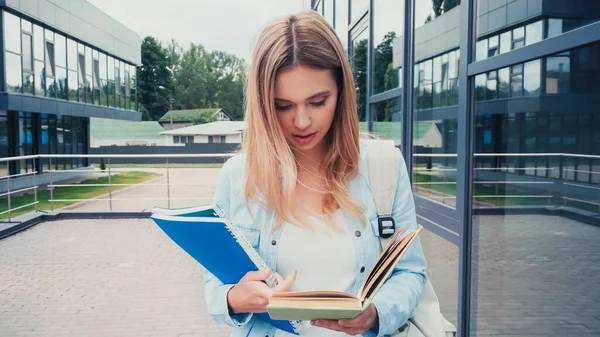 Красива студентська книга читання, стоячи поруч з будівлею — стокове фото