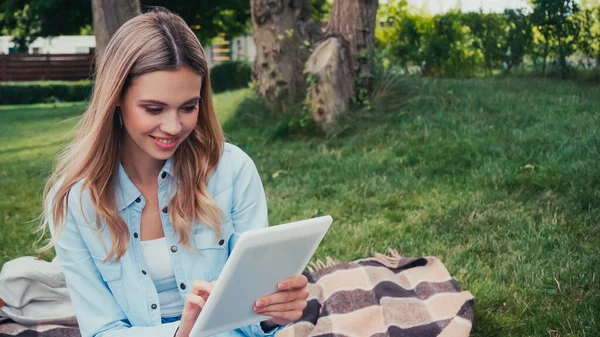Feliz joven estudiante usando tableta digital en el parque - foto de stock