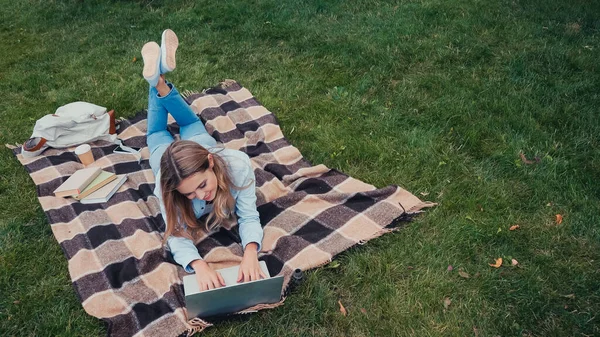 Visão aérea do estudante sorrindo usando laptop no cobertor no parque — Fotografia de Stock